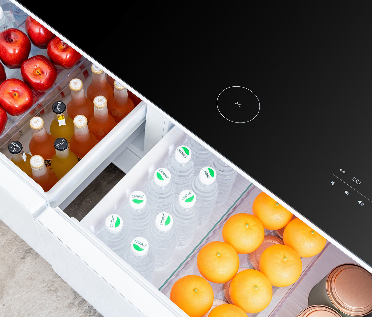 Offener, weißer Caso Sound & Cool Kühlschrank gefüllt mit Äpfeln, Getränkeflaschen, Wasserflaschen und Orangen.