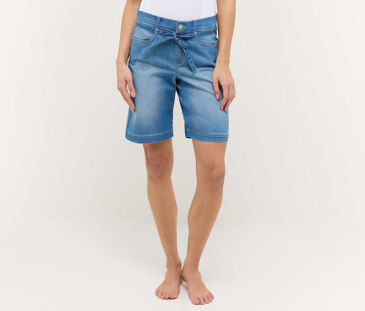 Frau trägt hellblaue Angels Denim »Lia City« Shorts mit Bindegürtel vor weißem Hintergrund.