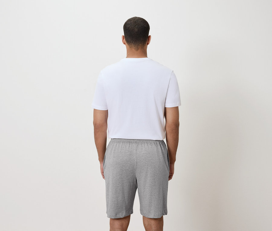 Rückansicht eines Mannes mit weißem T-Shirt und grauen Shorts.