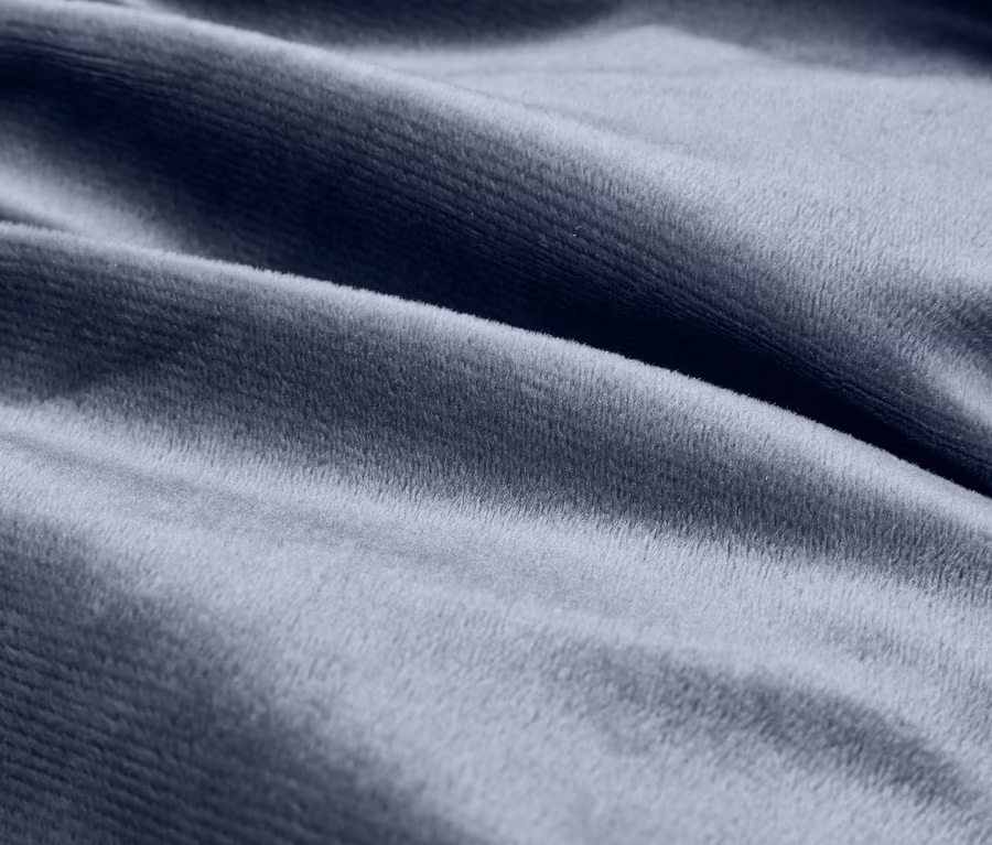 Nahaufnahme eines blaugrauen, weichen, samtartigen Stoffes mit sanften Falten.