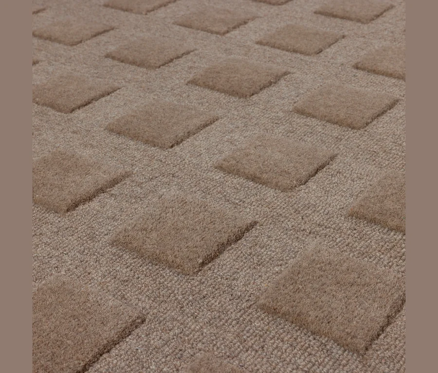 Beiger Teppich mit erhabenen, flauschigen Quadraten auf einem flacheren, gewebten Hintergrund.