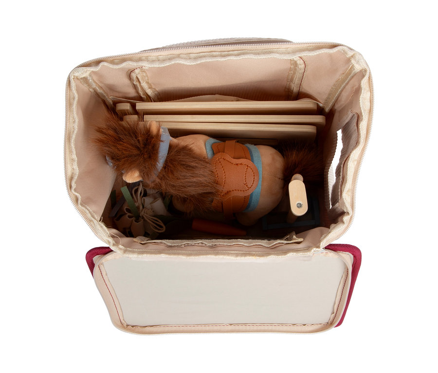 Offener Rucksack mit einem Small Foot Spiel-Set Pferd mit Stall, inklusive Holzstallteilen und einem Plüschpferd mit Sattel.