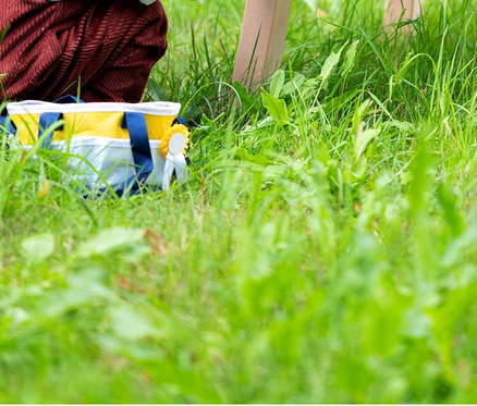Ein Junge sitzt auf einem Holzpferd, ein Mädchen steht daneben und spielt damit. Am Pferd ist ein Zaumzeug befestigt. Im Gras steht eine Tasche mit einem small foot Spielzeug-Pferdepflege-Set mit Tasche.