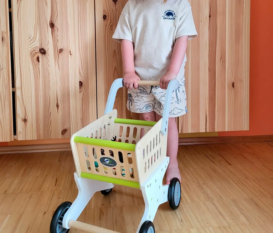 Mädchen schiebt einen »Trend« Einkaufswagen von small foot aus Holz in einem Kinderzimmer.