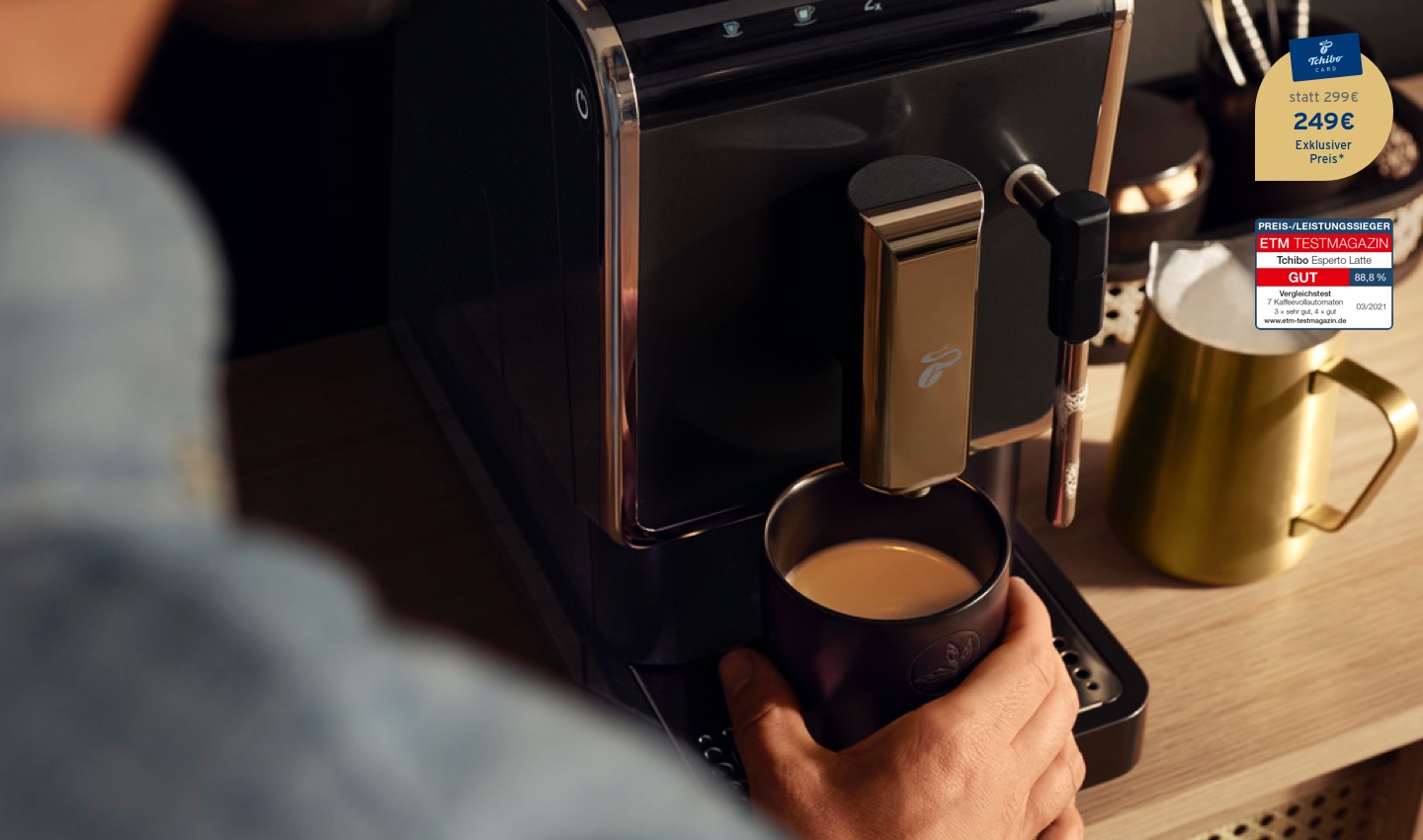 Der Esperto Latte auf einer Küchentheke mit einem frisch aufgebrühten Kaffee und einem goldenen Milchkännchen mit Milchschaum daneben