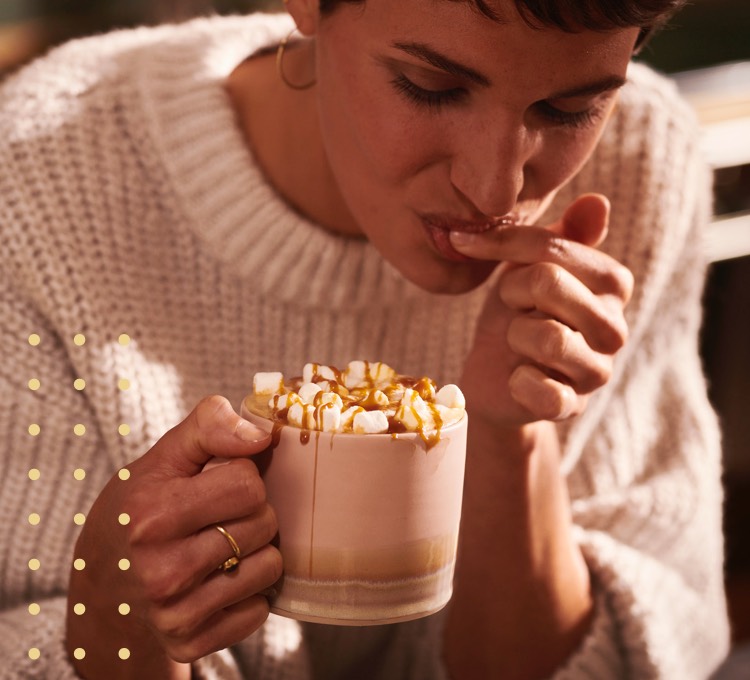 Eine Frau trinkt genüsslich ihren Kaffee aus ihrer Tasse.