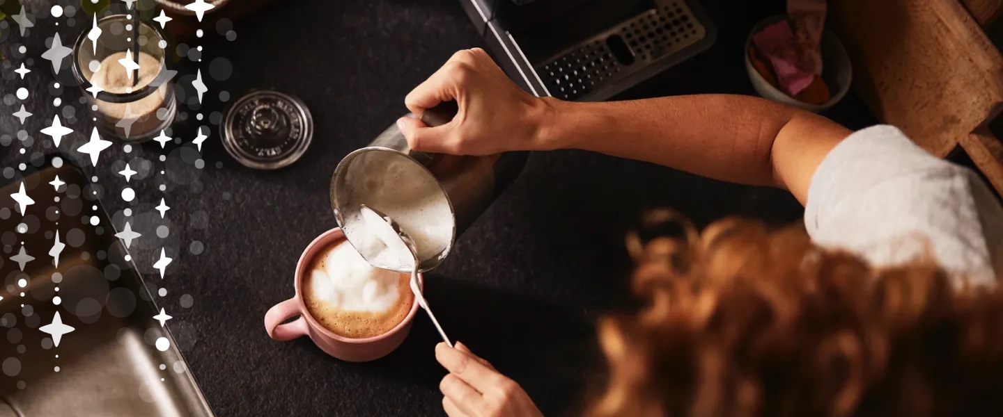 Ein kleines Mädchen schaut freudig und neugierig zu einem Mann hoch, der einen Kaffee trinkt.
