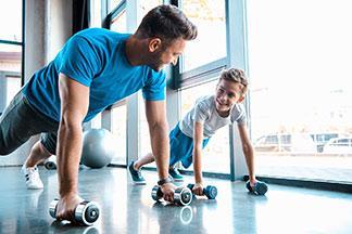 Vater und Sohn machen in ihren Sportshirts zusammen sport.