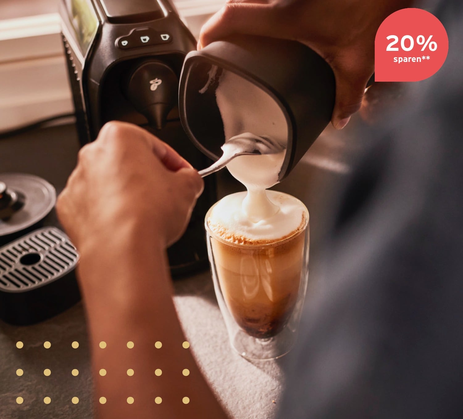 Milchschaum wird aus dem elektrischen Milchaufschäumer in eine Caffè Crema Glas gefüllt.