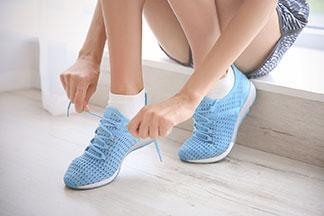 Eine frau zieht sich ihre blauen Sportschuhe an.