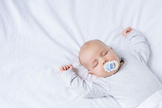 Ein Baby liegt auf einem Bettlaken.