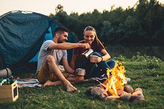 Ein Pärchen zeltet und sitzt an einem Lagerfeuer