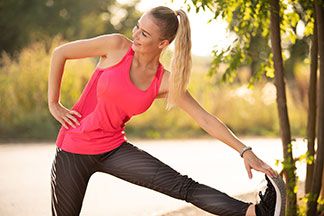 Die richtige Pflege für Ihre Jazzpants nach dem Sport: Eine blonde Frau in einem Sportoutfit macht Dehnübungen an einer Bank.