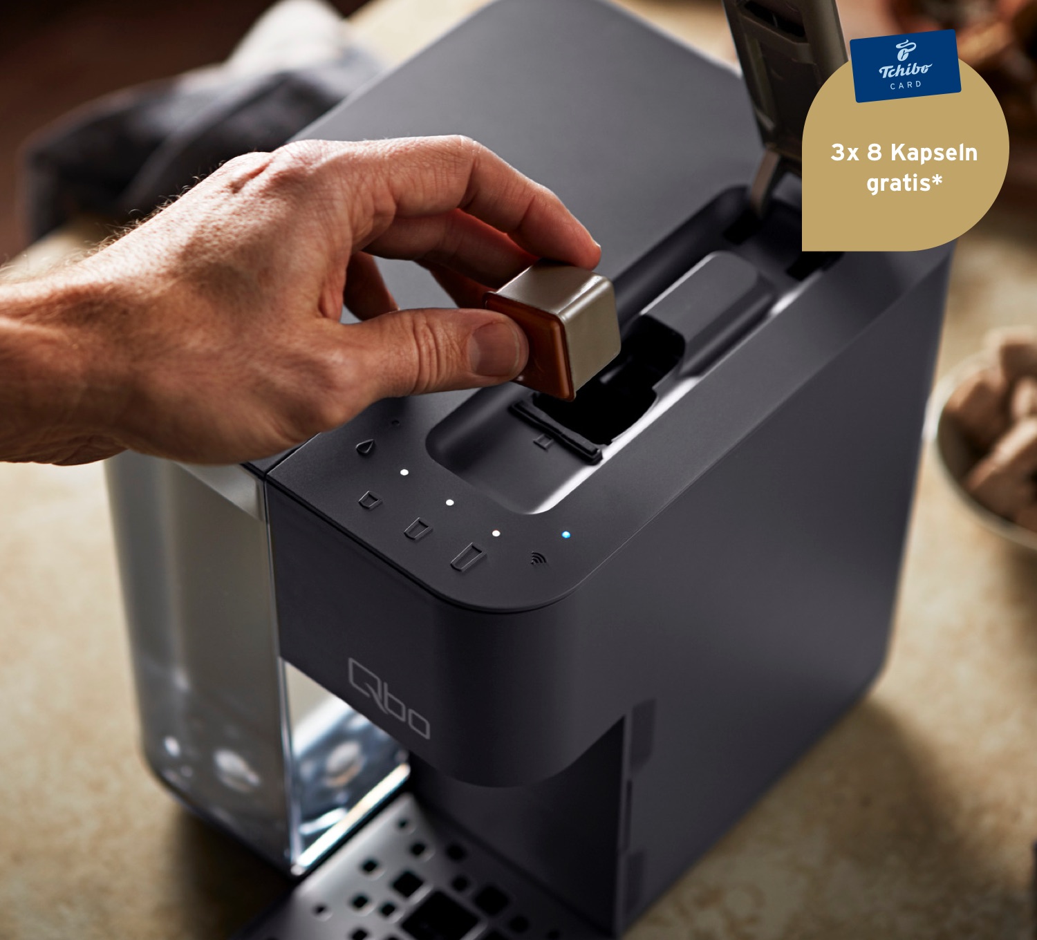 Ein Mann legt eine Qbo Kaffeekapsel in das Kapselfach einer Qb Touch in Basalt Grey