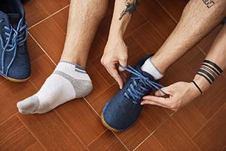 Ein Mann zieht sich seine blauen Sportschuhe an.