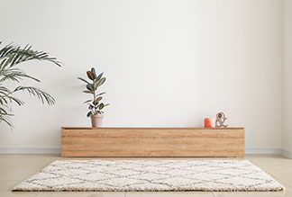Eins stylischer heller Teppich mit Rautenmuster liegt in einem modern eingerichteten Wohnzimmer.