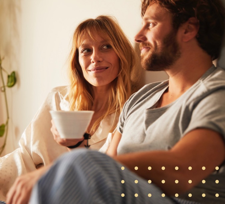Ein Mann und eine Frau sitzen auf einer Couch und genießen ihren Kaffee.