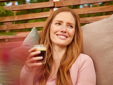 Frau trinkt frischen Kaffee aus einem Caffè Crema Glas