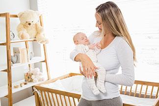 Eine Mutter hebt ein Baby aus dem Babybett