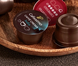 Cafissimo Caffè Crema und Espresso Kapseln liegen auf einer Holzschale