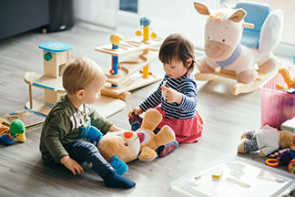 Zwei Kleinkinder spielen im Wohnzimmer.