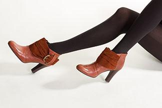 Eine Frau trägt elegante, braune Ankle-Boots