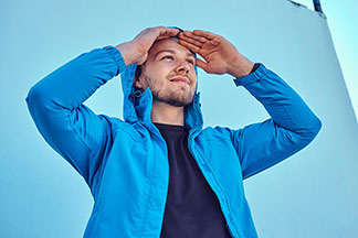 Eine Mann trägt eine blaue Jacke und schaut in die Ferne.