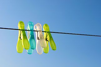 Die richtige Pflege für Ihre Sport-Tights: Verschiedenfarbige Wäscheklammern auf einer Wäscheleine vor blauem Himmel.