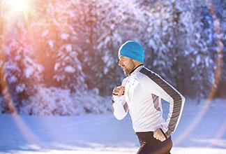 Ein Mann joggt im Park mit einer weißen Sportjacke.