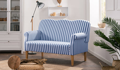 Auf dem weiß-blau-gestreiften Küchensofa, das neben einem Küchenschrank steht, sieht man nicht so viele Flecken.