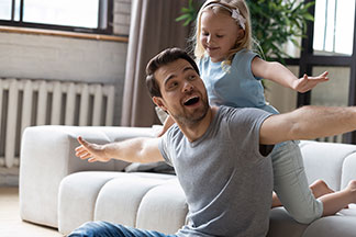 Ein Vater spielt mit seiner Tochter im Wohnzimmer.