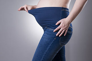 Eine schwangere Frau trägt eine Jeans mit Gummiband.