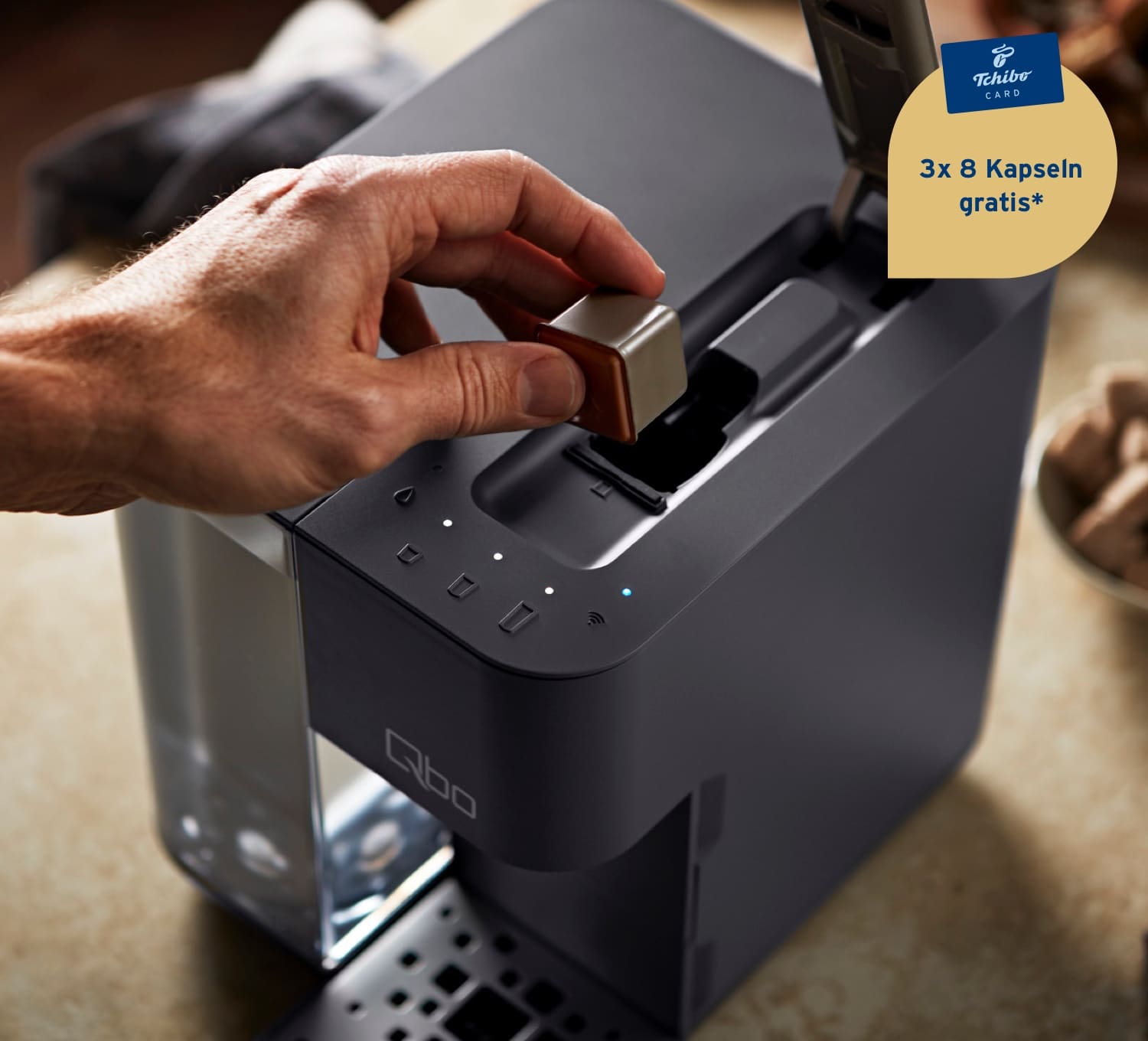 Ein Mann legt eine Qbo Kaffeekapsel in das Kapselfach einer Qb Touch in Basalt Grey