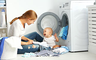 Eine Mutter mit Ihrem Kind sitzen vor der Waschmaschine.