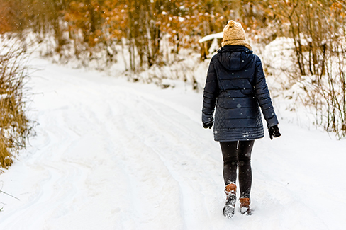 Eine Frau trägt eine schwarze Leggings und stampft durch den Schnee.