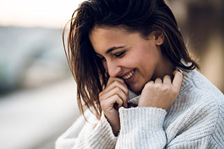 Eine Frau kuschelt sich in ihren grauen Strickpullover.