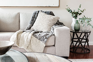 Ein Sofa mit weißem Bezug und einer gemütlichen Wolldecke für den klassischen Wohnzimmerlook.
