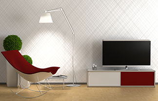 In einem Wohnzimmer steht ein rot-weißes Lowboard auf dem ein Fernseher steht, dazu ein Sessel mit rotem Bezug und eine Stehlampe.