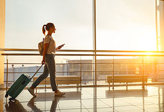 Eine Frau zieht ihren Hartschalenkoffer am Flughafen hinter sich her.