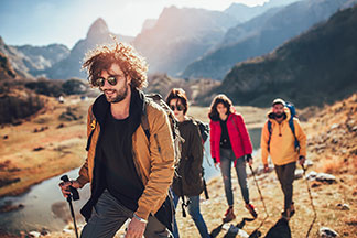 Eine Gruppe junger Leute, die Outdoorbekleidung tragen, wandern in einer bergigen Landschaft.