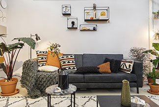 Dekokissen als Hingucker: Eine dunkelgraue Couch mit beigen, schwarzen und gemusterten Dekokissen.