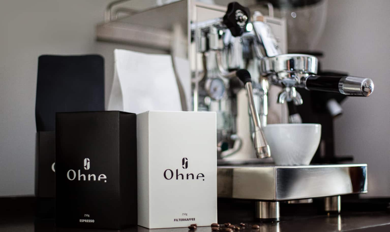 Zwei Packungen Kaffee der Rösterei OHNE Coffee stehen neben einem Siebträger