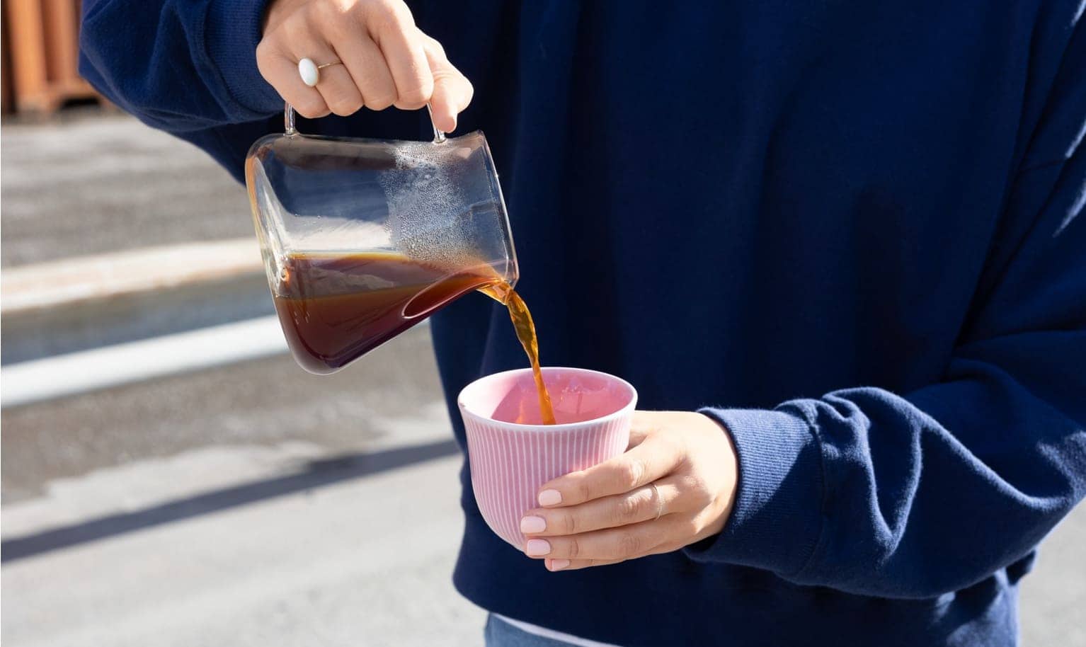 Person gießt Filterkaffee in eine pinke Tasse ein.