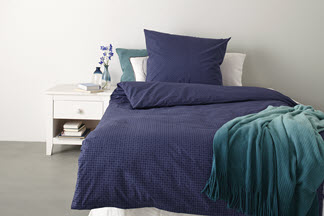 Ein Bett mit dunkelblauer Perkal-Bettwäsche