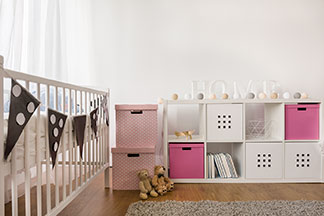 Ein weißes Babybett mit Girlanden und rosa Dekoration.