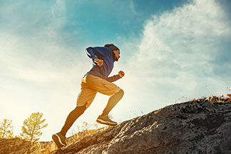 Die richtigen Socken für den Sport: Ein Mann joggt einen Berg hinauf.