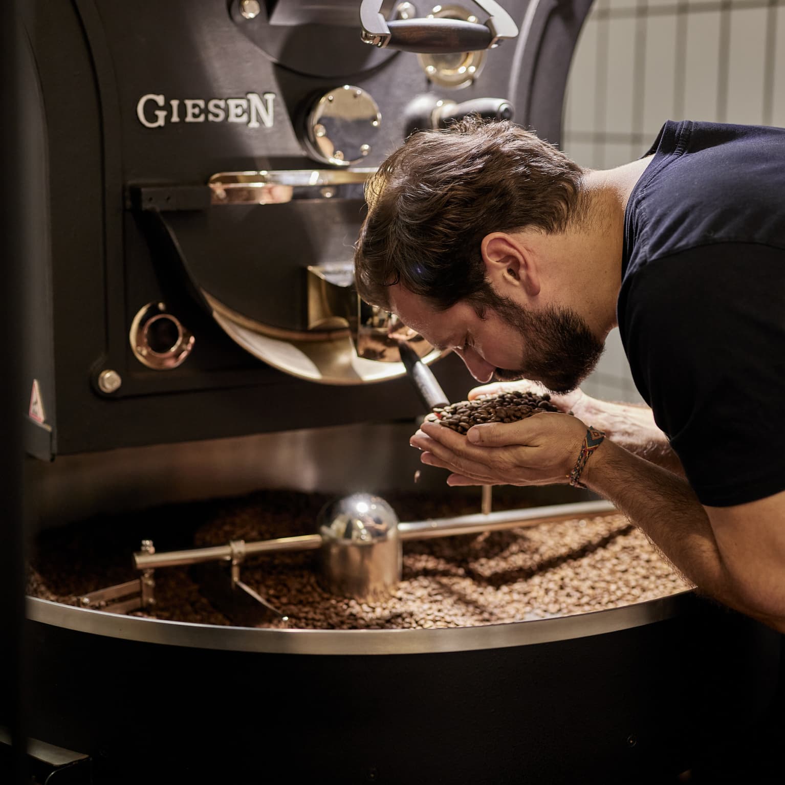 Inhaber der Rösterei richt an Kaffeebohnen, die er aus der Trommel entnommen hat