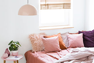 Kopfkissenbezüge sorgen für Gemütlichkeit: Ein Bett mit vielen quadratischen Kissen in unterschiedlichen Größen und Farben.
