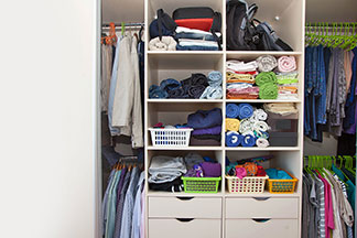 Ordnungshelfer für den Schrank: Blick in einen offenen Kleiderschrank, der dank Hängesystemen, Schubladen, diversen Schachteln und Boxen sehr gut strukturiert ist.