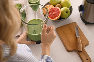 Eine Frau bereitet einen Smoothie vor.